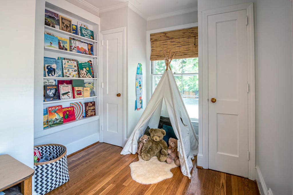 Charming children's room featuring a play tent, stuffed toys, and a bookshelf filled with colorful books.