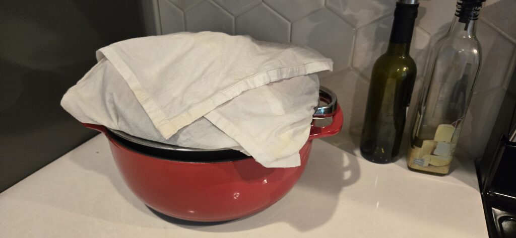 Homemade Greek yogurt straining through flour-sack cloth in a colander.